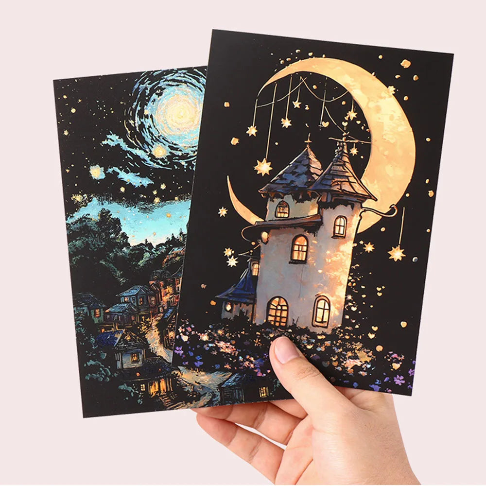 A hand holds a dark card featuring a glowing moon and castle silhouette with stars, part of a glow-in-the-dark scratch art ki