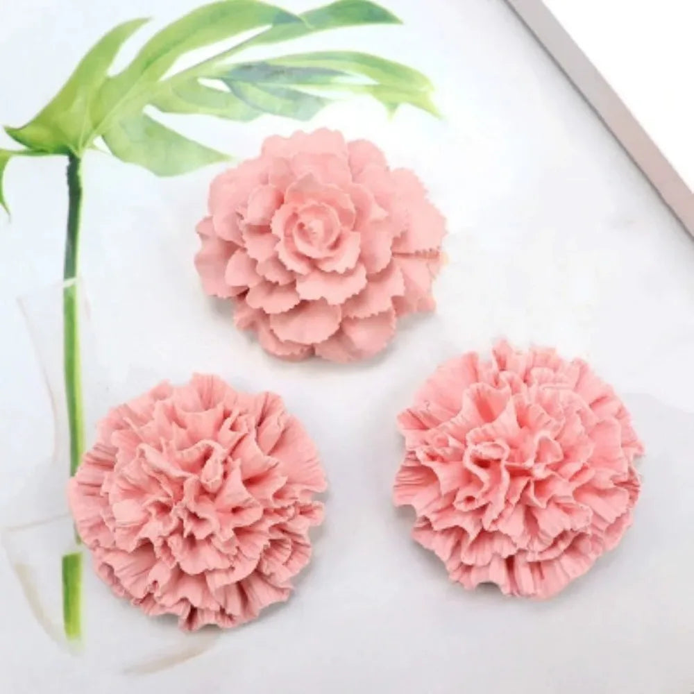 Three pink floral 3D silicone molds for candles, soap, and baking displayed on a white surface with green leaves.