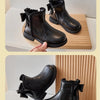 A pair of black girls' ankle boots with a bow-knot detail and side zipper displayed on a wooden surface.