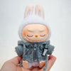 A Labubu doll wearing a gray hoodie and headphones, held in a person's hand.