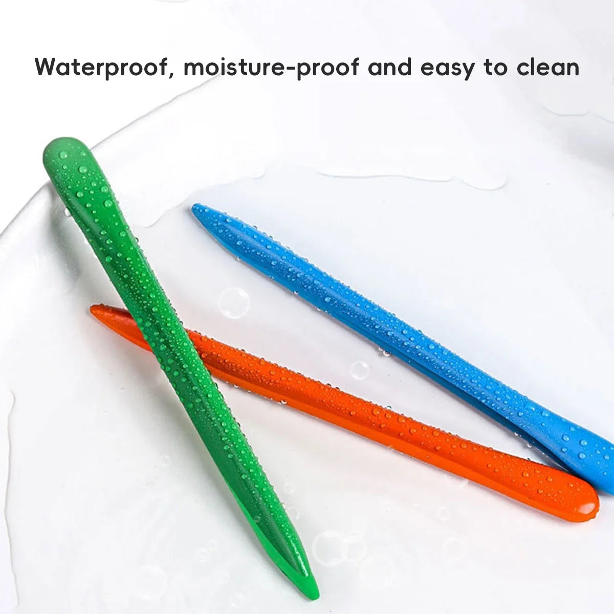 Three triangular colored crayons in green, blue, and orange resting on a white surface.