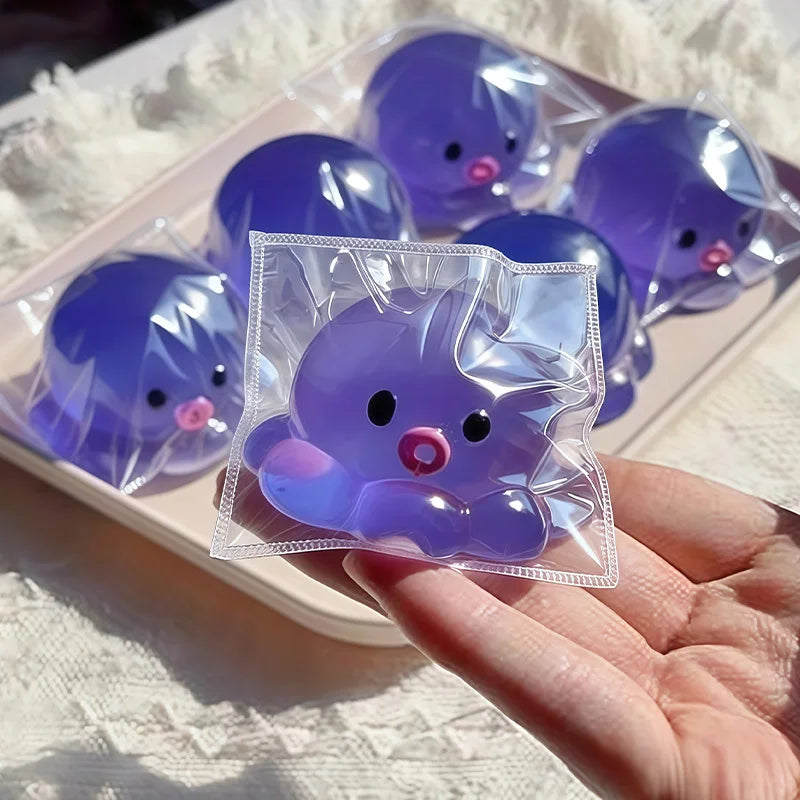 A hand holds a clear plastic squishy bubble squid stress relief toy with purple and pink accents.