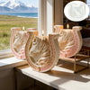 A set of white and pink ceramic candle molds shaped like horses with Celtic knot designs displayed on a windowsill.