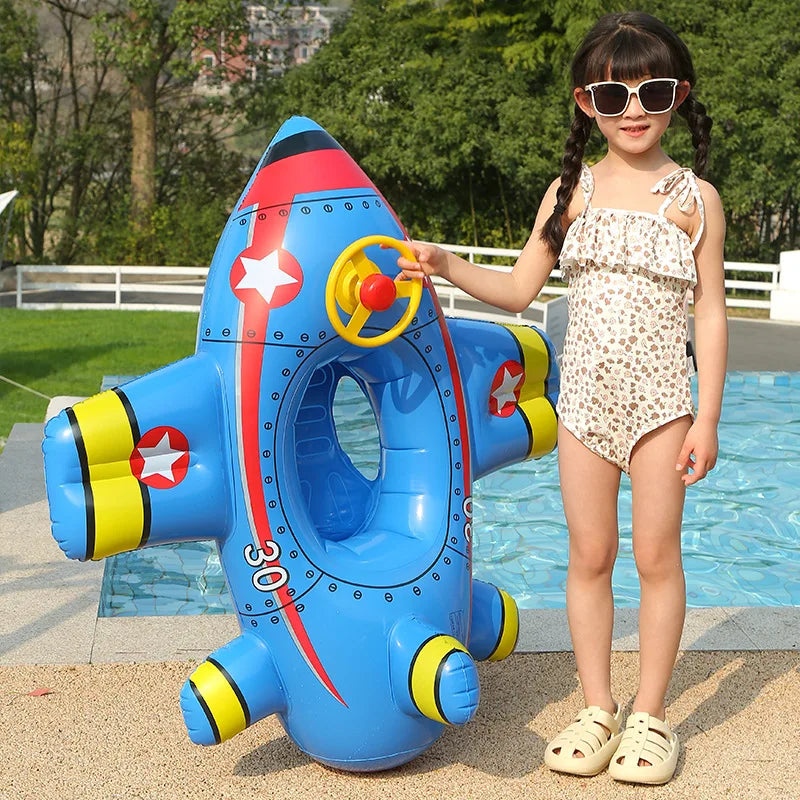 A young girl holds a blue inflatable aircraft swim ring for kids outdoors.