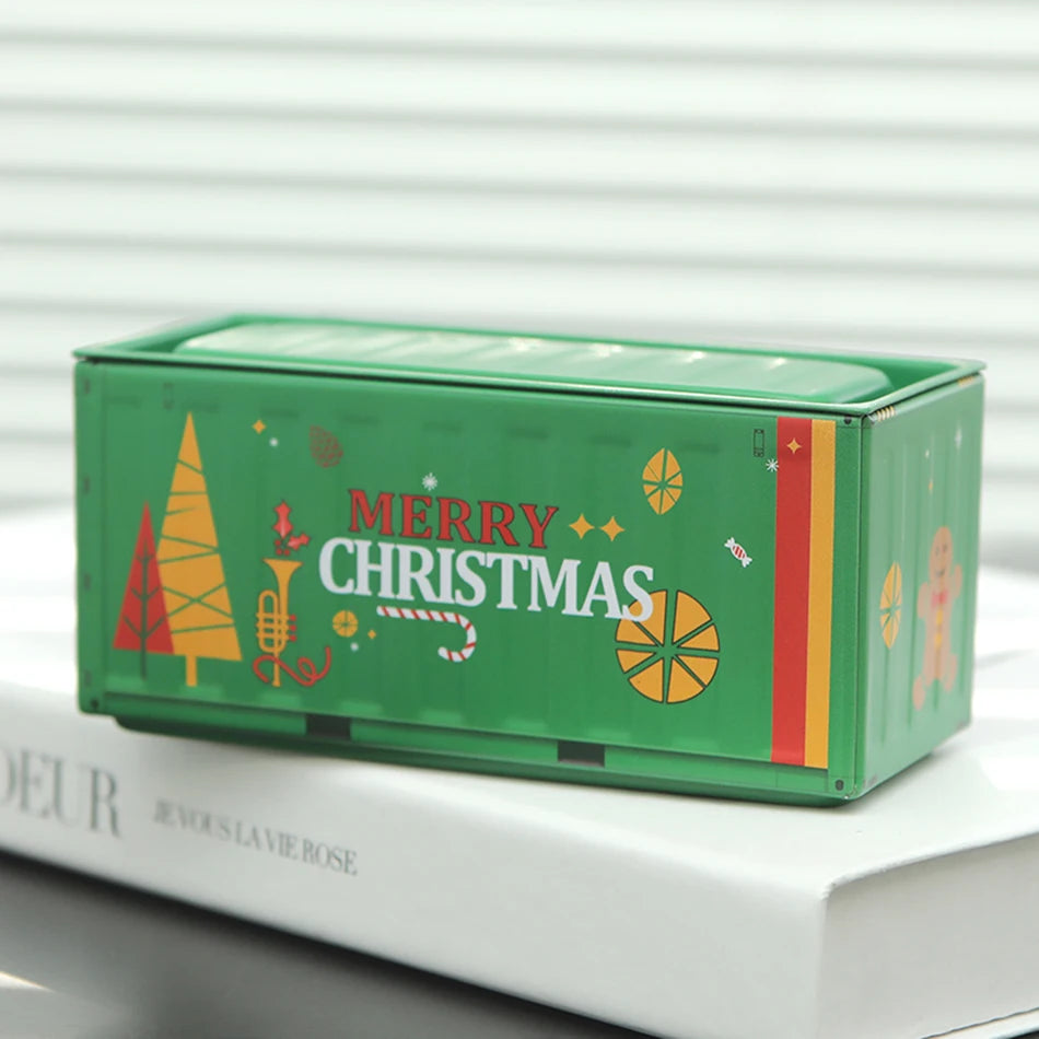 A green storage box decorated with Christmas motifs, including a tree, ornaments, and lettering.