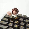 A close-up of a brown female figure collectible keycap blind box with a pink base and black keycaps.