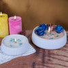 A collection of candles and blue fabric roses displayed on a wooden surface.
