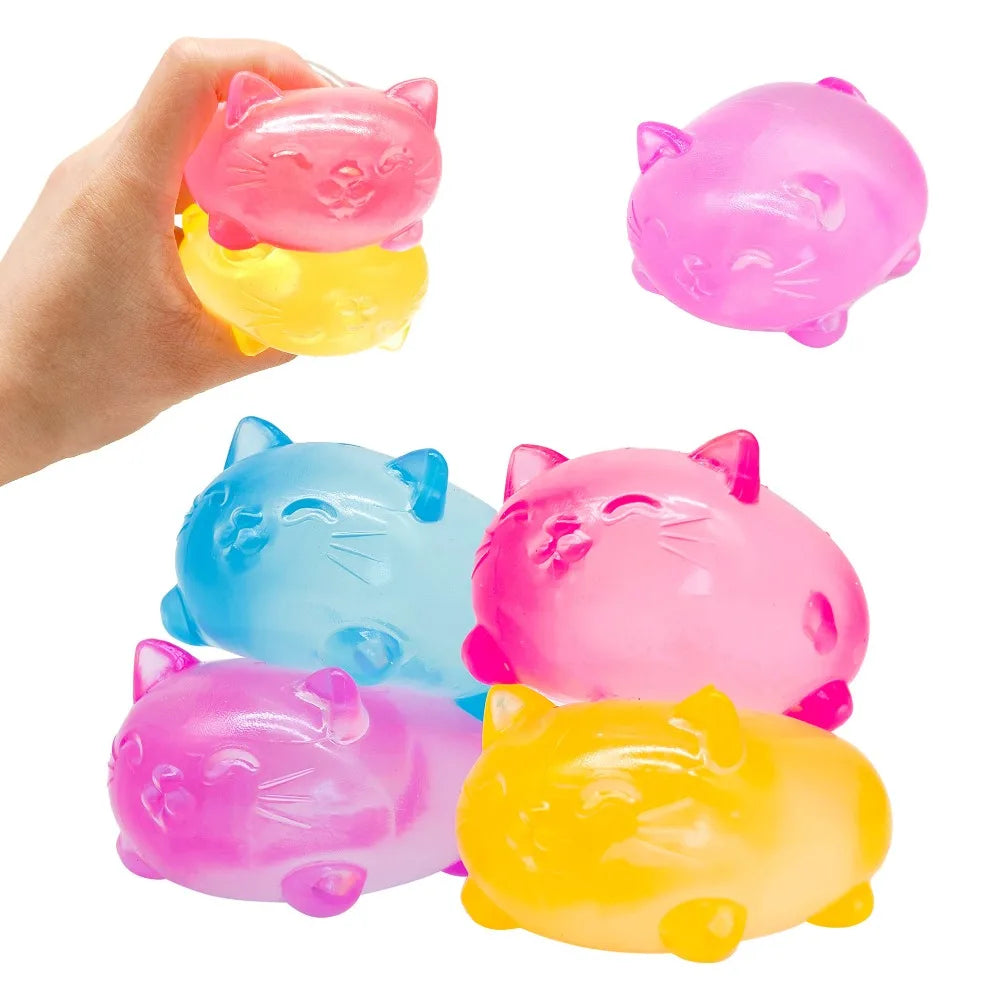 A hand holds a pink cat squishy toy next to a bright yellow one.