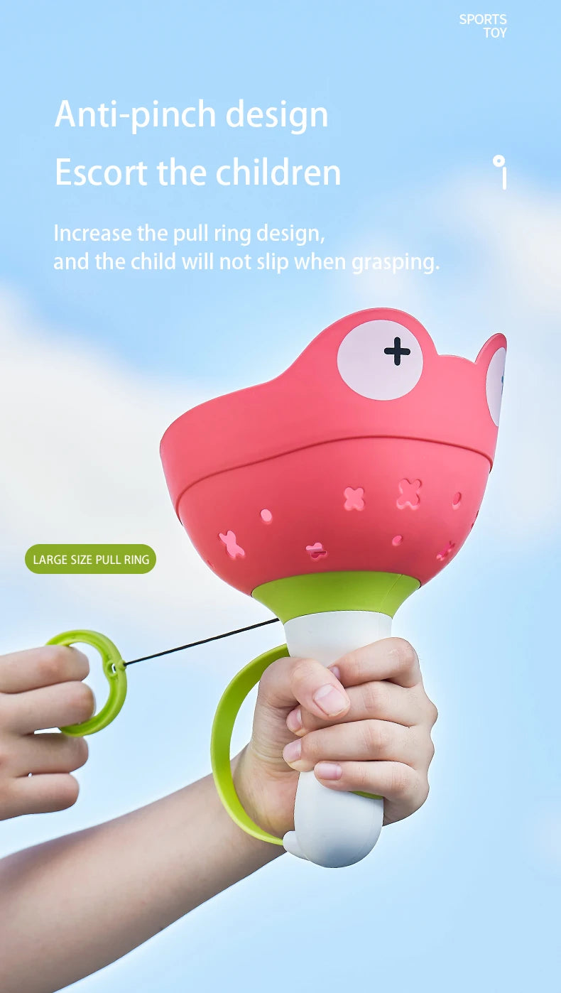 A hand is holding a pink flying saucer toy with a green pull ring, demonstrating its anti-pinch design.