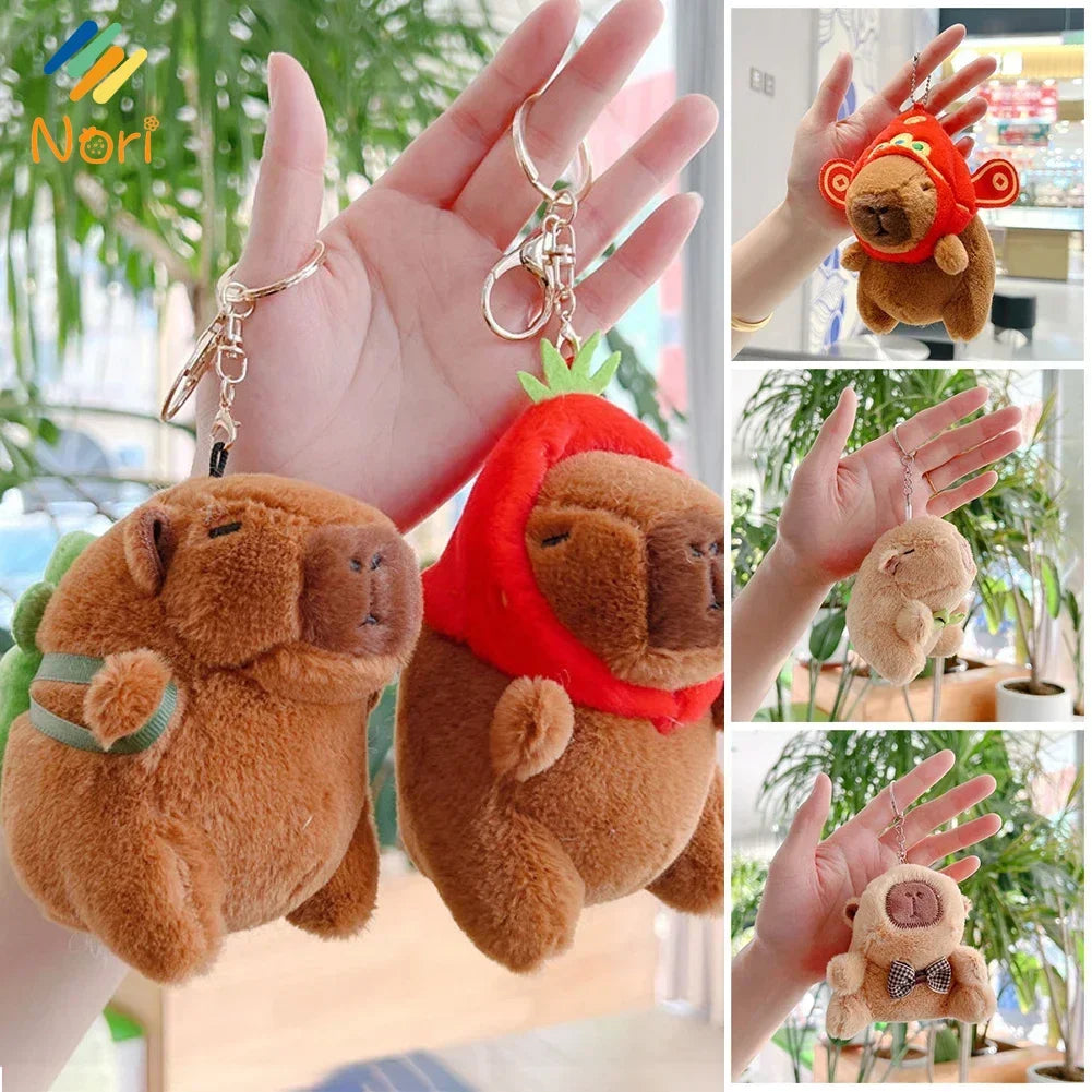 A fluffy brown capybara plush toy with a red leaf accessory is shown being held by a hand.