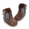 A pair of brown baby western booties with decorative stitching and a soft non-slip sole.