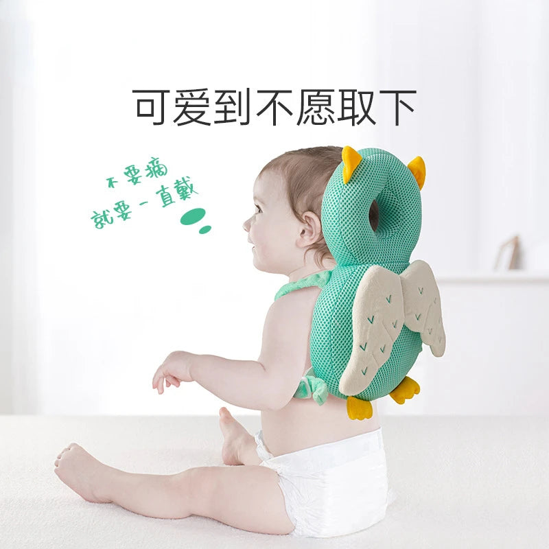 A baby is wearing a soft green and yellow stuffed animal backpack pillow while lying down.