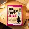 A box of The Killer Isn't Alice murder mystery puzzle book with a pink cover resting on a wooden table.