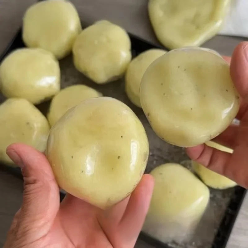 A hand holds a yellow mashed potato squeeze toy stress reliever with a light green color.