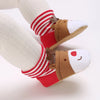 A pair of adorable animal-themed baby first walker shoes with brown and white fabric and red striped socks.