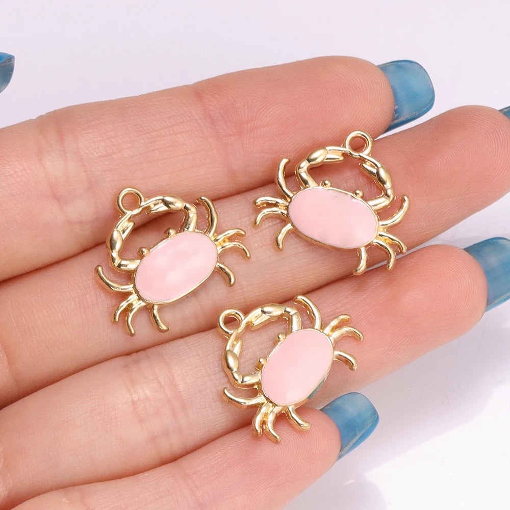 Gold-toned enamel marine life charms shaped like crabs and starfish displayed on a hand.