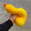 A hand is squeezing a bright yellow, elongated squishy duck fidget toy against a gray background.