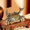 A brass crab figurine statue resting on a wooden box.