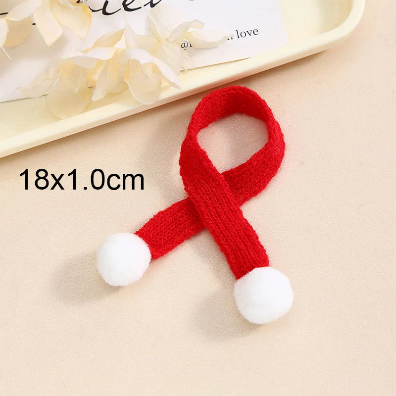 A red knitted Christmas hat or scarf with white pom-poms shown on a light background.