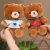 Two brown teddy bears wearing football jerseys, one blue and white, and the other red, being held by a hand.