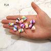 A hand holds a collection of ten colorful polymer clay marshmallow charms for DIY crafts.