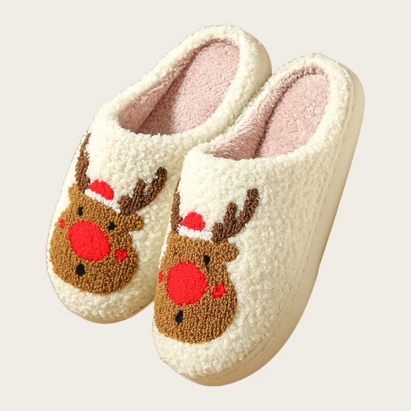 A pair of white plush indoor slippers shaped like reindeer heads with brown accents and pink lining.