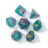 A set of seven polyhedral acrylic dice in various shades of teal and purple scattered on a white surface.