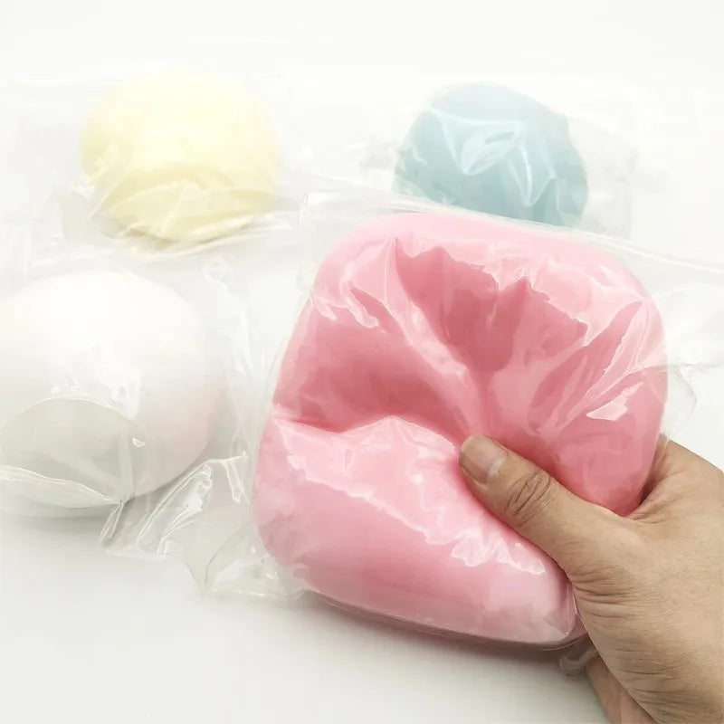 A hand holds a large pink squishy stress ball next to smaller squishies in a clear plastic bag.