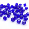 A pile of deep blue faceted bicone crystal glass beads for jewelry making.
