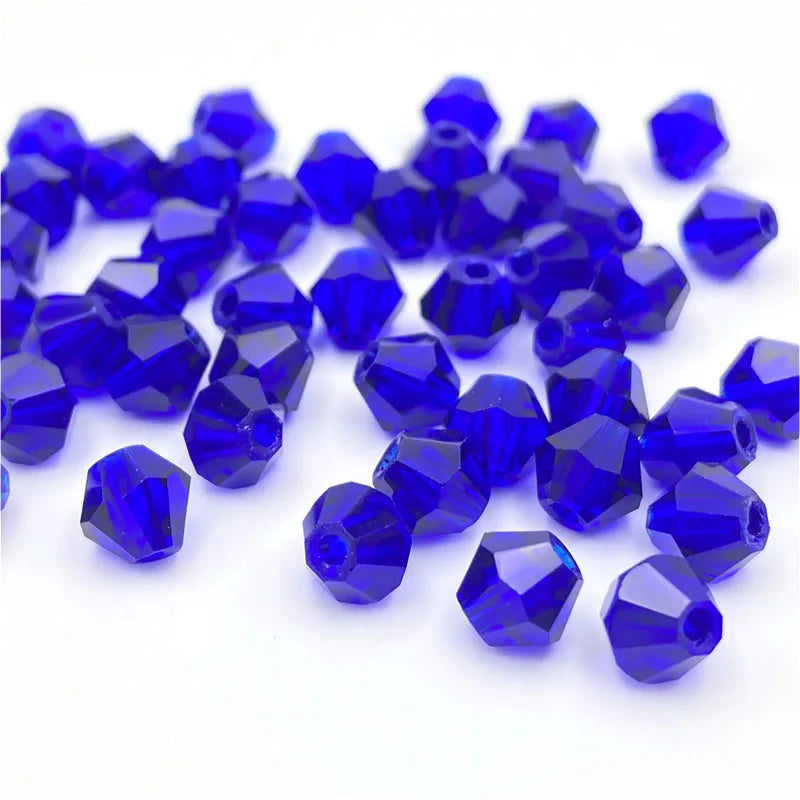 A pile of deep blue faceted bicone crystal glass beads for jewelry making.