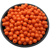 A pile of small, round, orange acrylic beads for jewelry making in a black bowl.