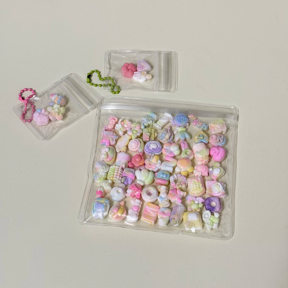 A clear plastic container filled with various pastel-colored squishy fidget toys and a small green beaded chain.