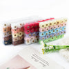 A collection of 35 plush fur pom pom beads in various colors packaged in clear plastic for jewelry making