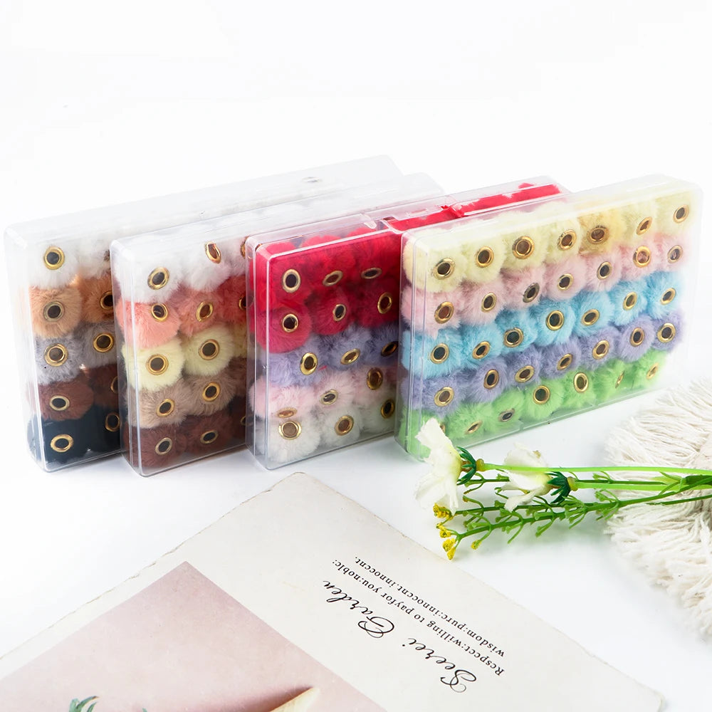 A collection of 35 plush fur pom pom beads in various colors packaged in clear plastic for jewelry making