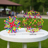 A colorful expandable magic ball stress relief toy with a mesh structure displayed on a white table.