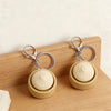 A beige fidget keychain with a smooth ball and silver clasps resting on a wooden surface.
