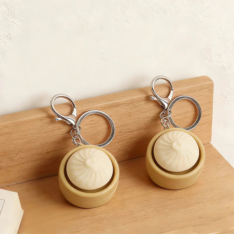A beige fidget keychain with a smooth ball and silver clasps resting on a wooden surface.