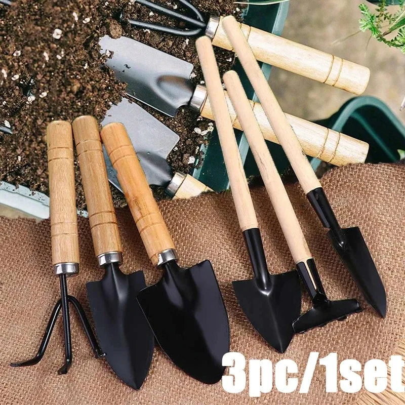A set of three mini gardening tools with wooden handles and black blades resting on brown burlap fabric.