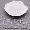 A white ceramic dish filled with small, translucent water drop glass beads for jewelry making