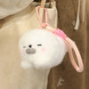 A white seal plush toy with a gray nose and an octopus-themed pink strap is hanging on a hanger.