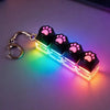 A keyboard keychain fidget toy featuring black silicone paw prints and a multi-colored LED light.