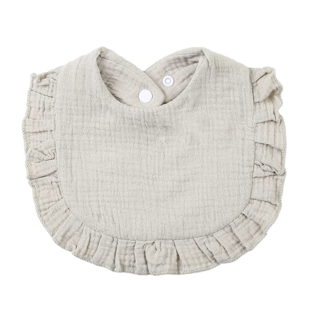 A light beige ruffled muslin cotton baby bib with an adjustable snap closure.