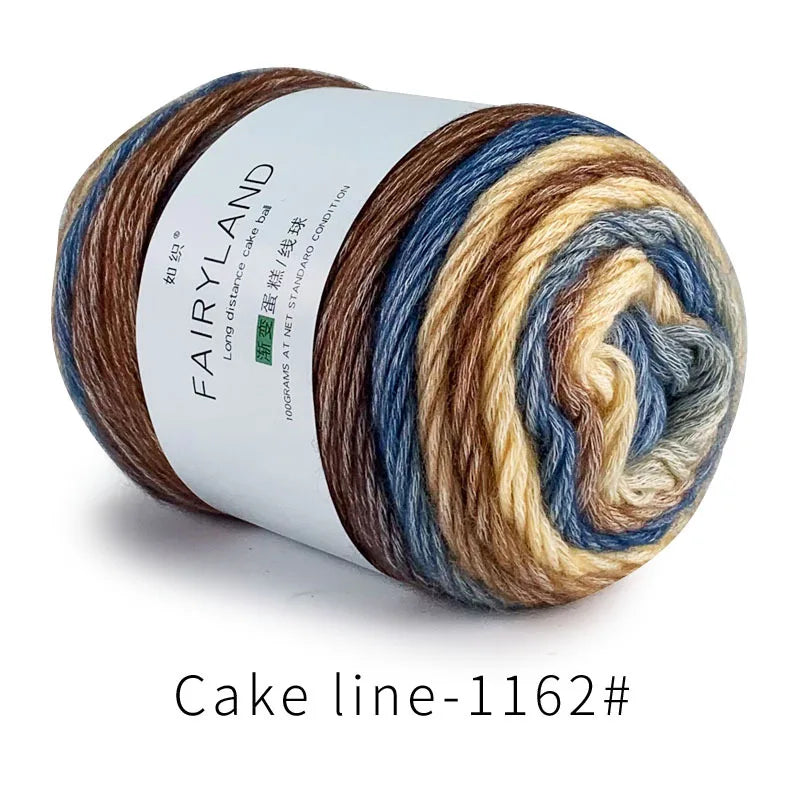 Spool of gradient rainbow cotton-wool yarn showing various shades of brown, blue, and cream.
