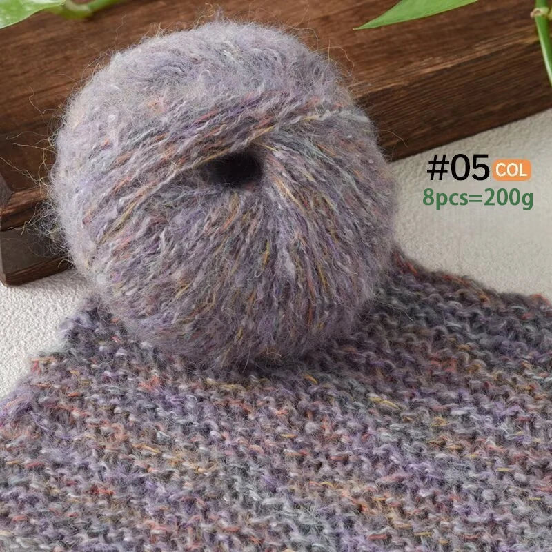 A ball of soft purple gray alpaca blend yarn resting on a knitted fabric background.
