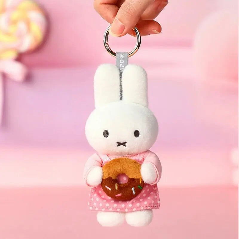 A white bunny plush keychain charm with pink accents and a donut detail is being held by a hand.