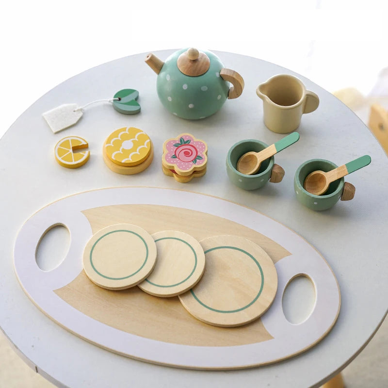 A wooden pretend play kitchen set featuring a green coffee maker and various tea accessories on a white table.
