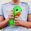 A person is holding a bright green squeeze duck stress relief toy against a gray t-shirt.