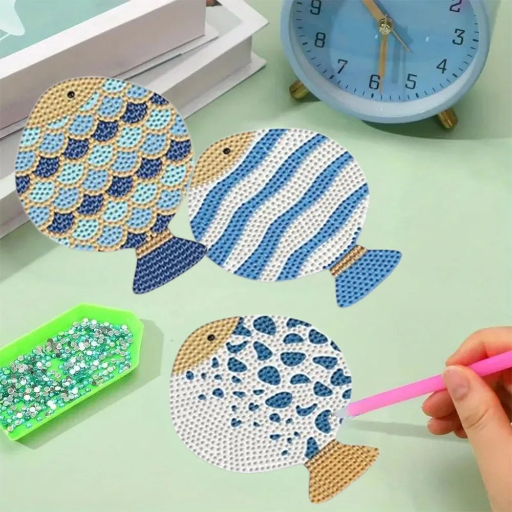 Eight piece diamond painting coasters featuring various fish designs and a clock on a light green surface
