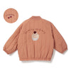 A peach-colored padded jacket featuring a embroidered text and a cherry graphic on the back, with a circular patch nearby.