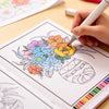 A hand is coloring a botanical illustration in a coloring book with various colored pencils.